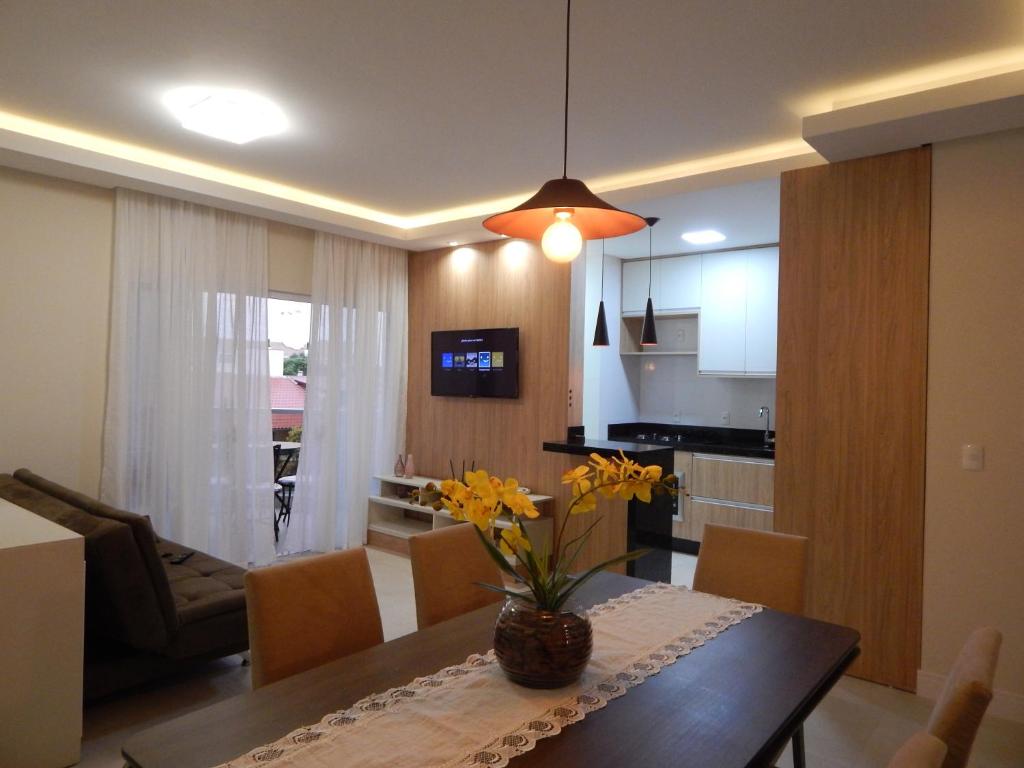 Apto. Novo e decorado. في بومبينهاس: مطبخ وغرفة طعام مع طاولة مع زهور صفراء
