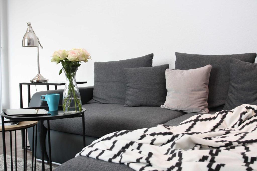 a living room with a couch and a vase of flowers on a table at Ferienwohnung Bauhausblick in Dessau