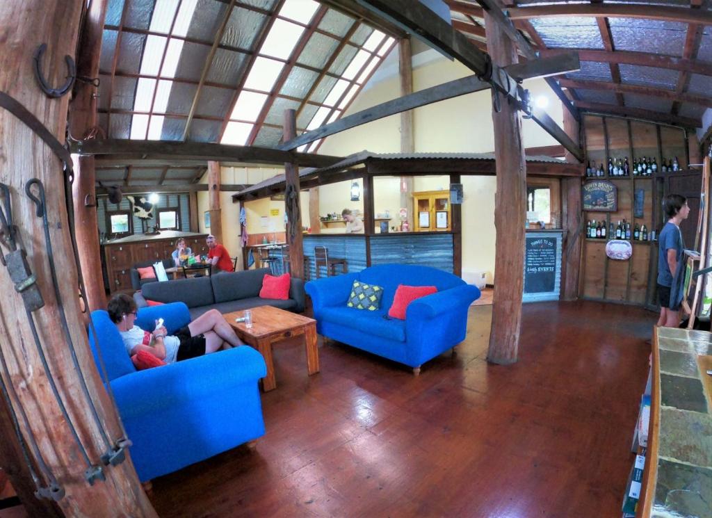 a living room with blue couches and a table at Woolshed Eco Lodge in Hervey Bay
