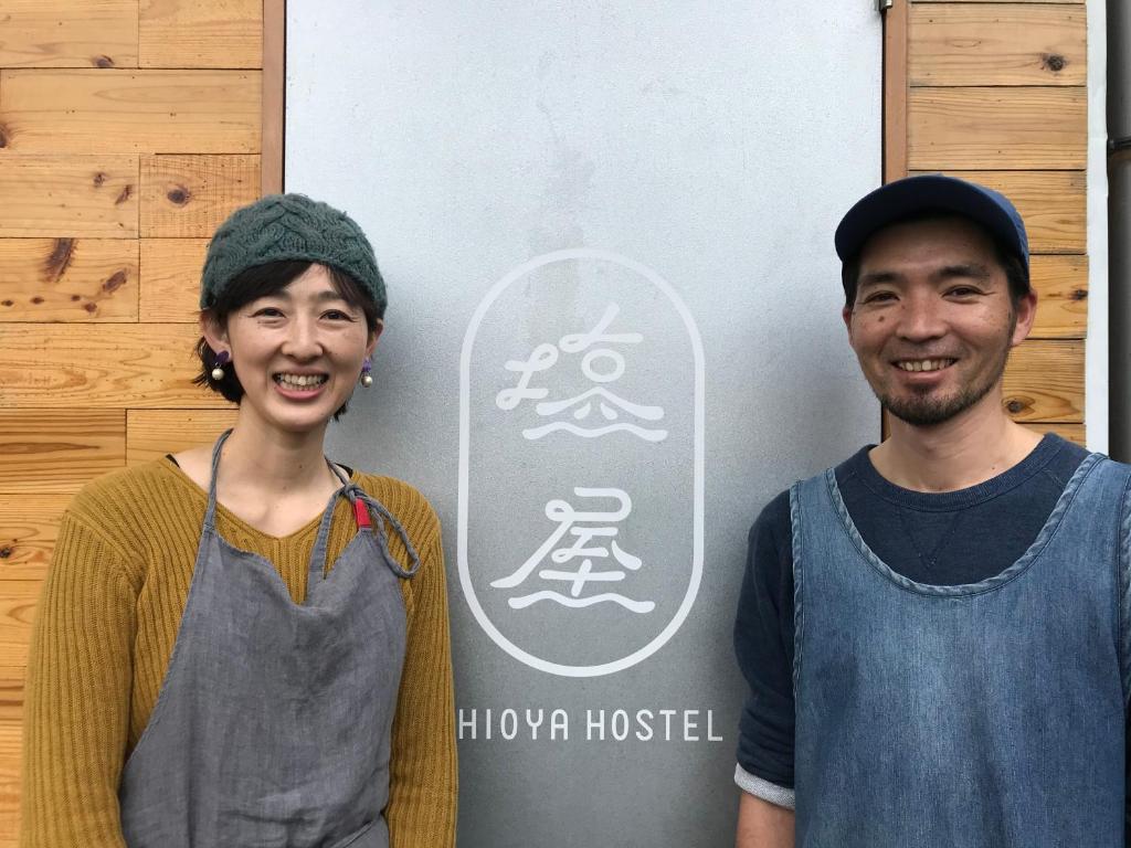 a man and a woman standing in front of a snowboard at Shioya Hostel in Akune