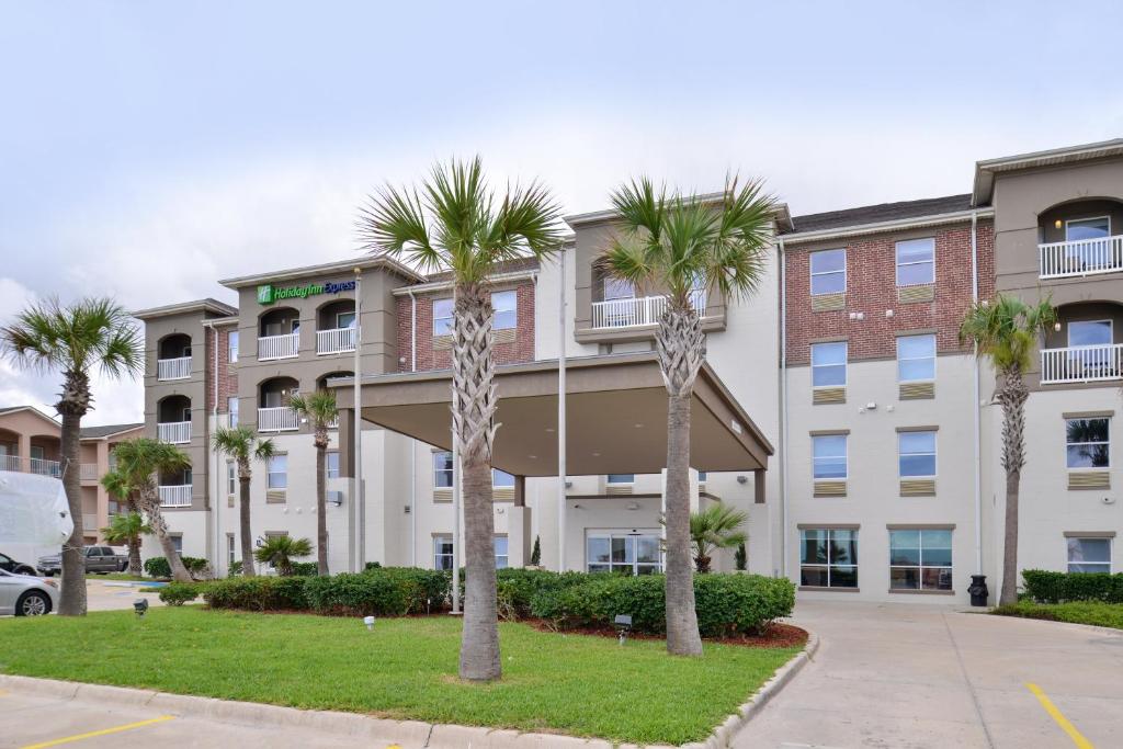 an apartment building with palm trees in front of it at Holiday Inn Express & Suites Corpus Christi-N Padre Island, an IHG Hotel in Corpus Christi