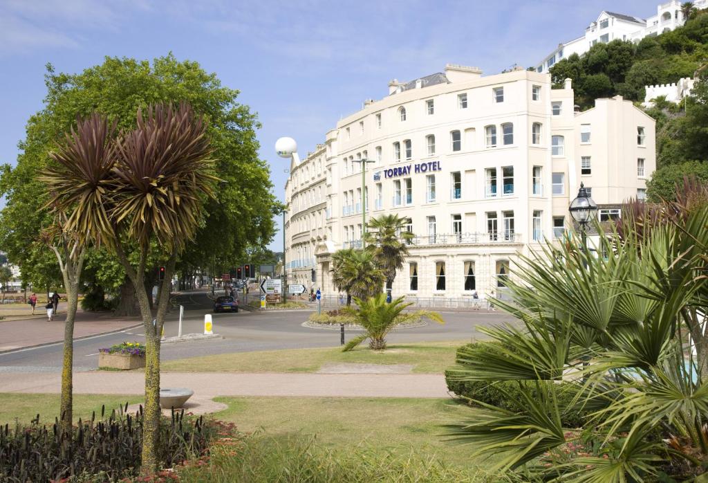 un edificio blanco en una calle con palmeras en The Caledonian Torbay Hotel, en Torquay