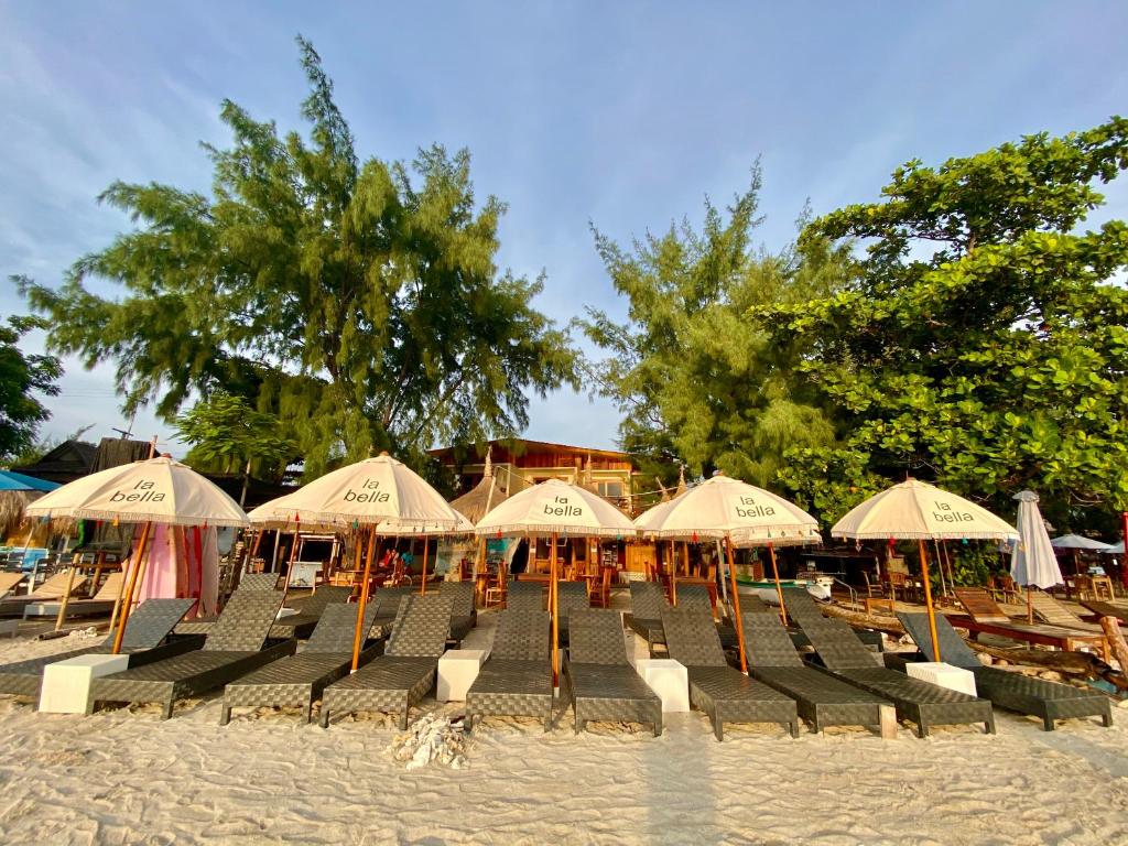 een groep stoelen en parasols op een strand bij La Bella - Hotel Villa & Spa in Gili Trawangan