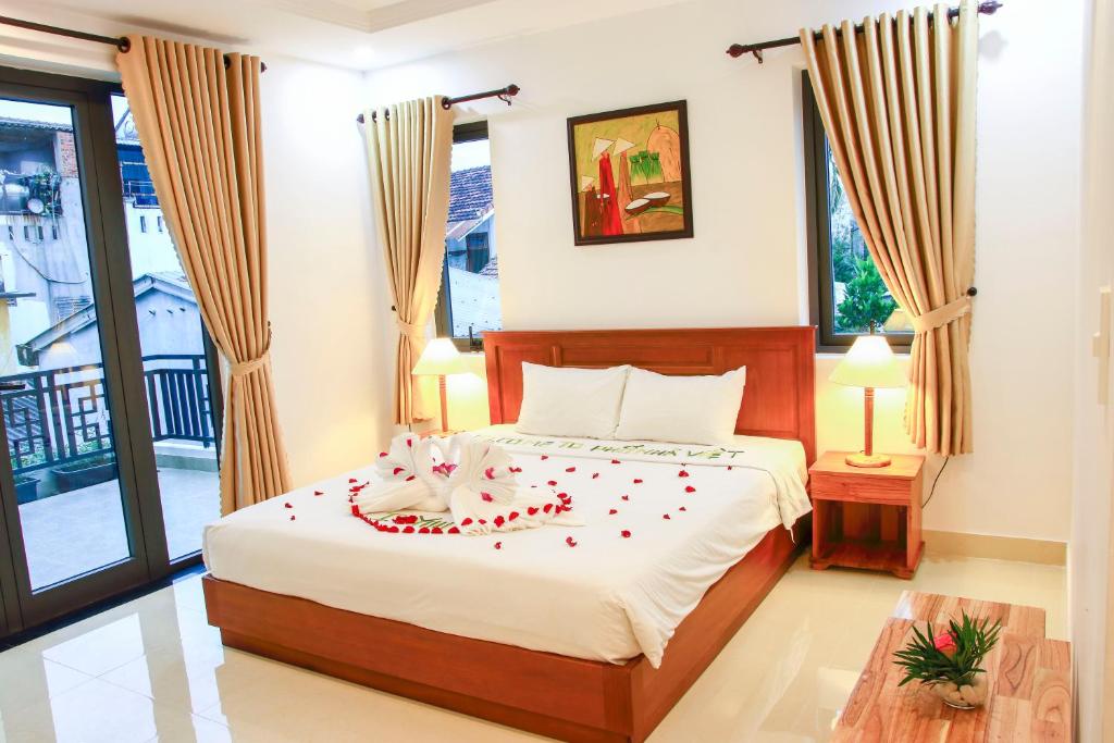 ein Schlafzimmer mit einem Bett mit Rosen darauf in der Unterkunft Hoi An Town Of Viet House Homestay in Hoi An
