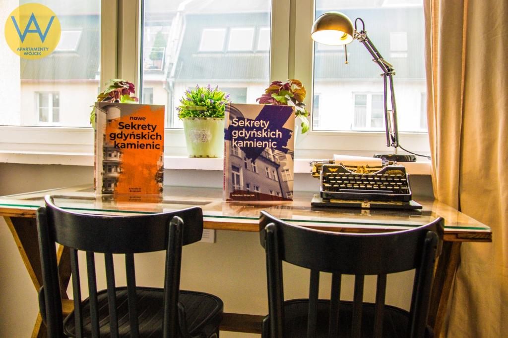 a desk with two chairs and a lamp and a window at Apartamenty Wójcik Loft in Gdynia