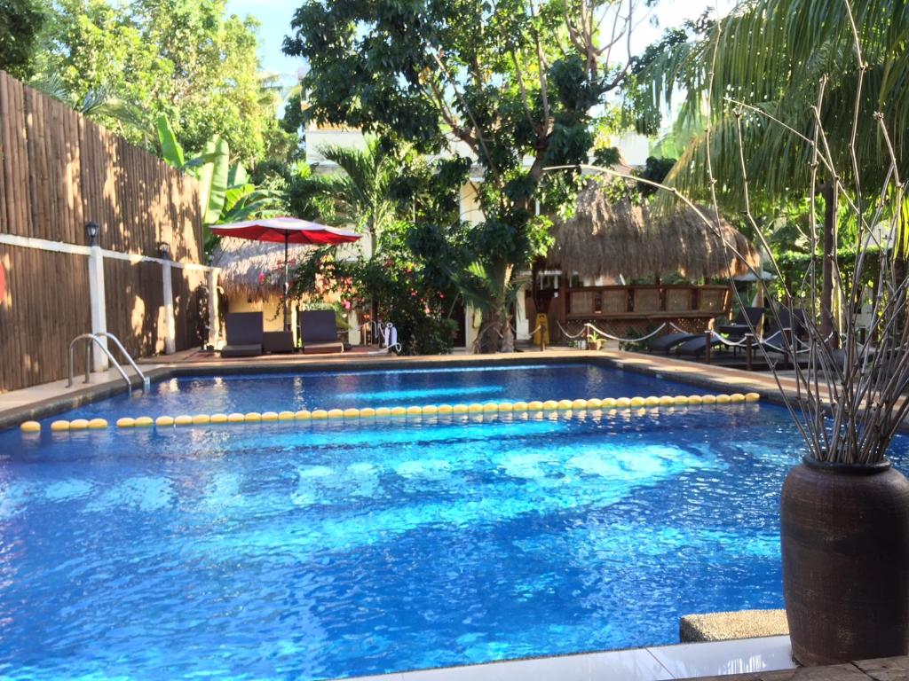 a large swimming pool with a red umbrella and chairs at Palms Cove Resort in Panglao Island