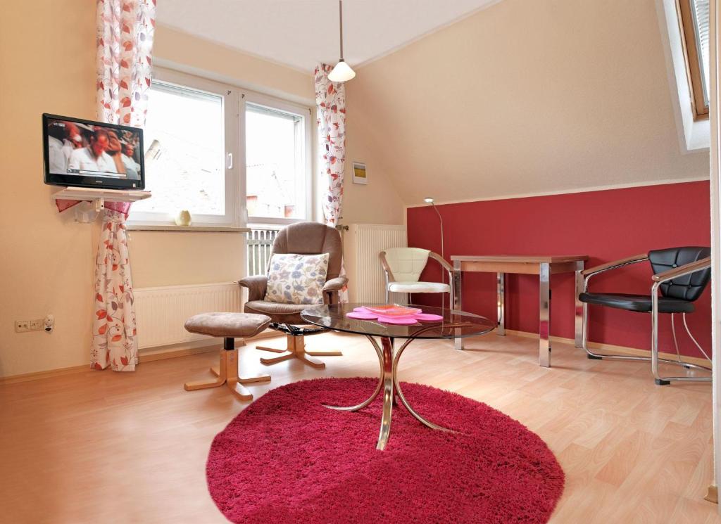 uma sala de estar com uma parede vermelha e uma mesa e cadeiras em Ferienwohnungen Am Lotsenstieg Morgensonne em Timmendorf