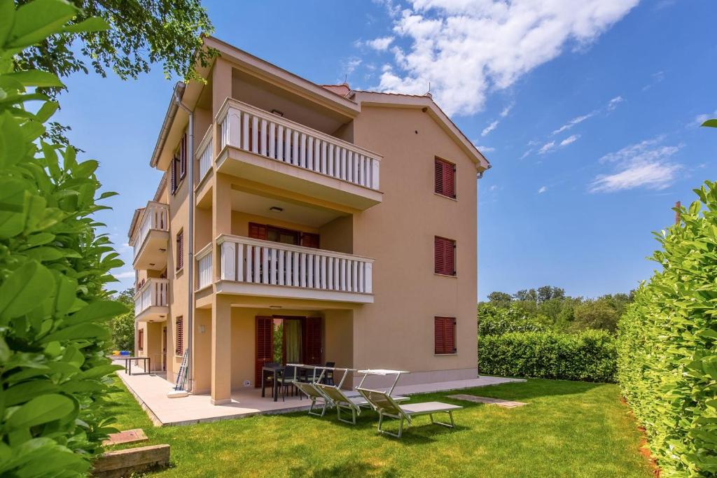 a building with chairs and tables in a yard at Apartments Mike in Malinska