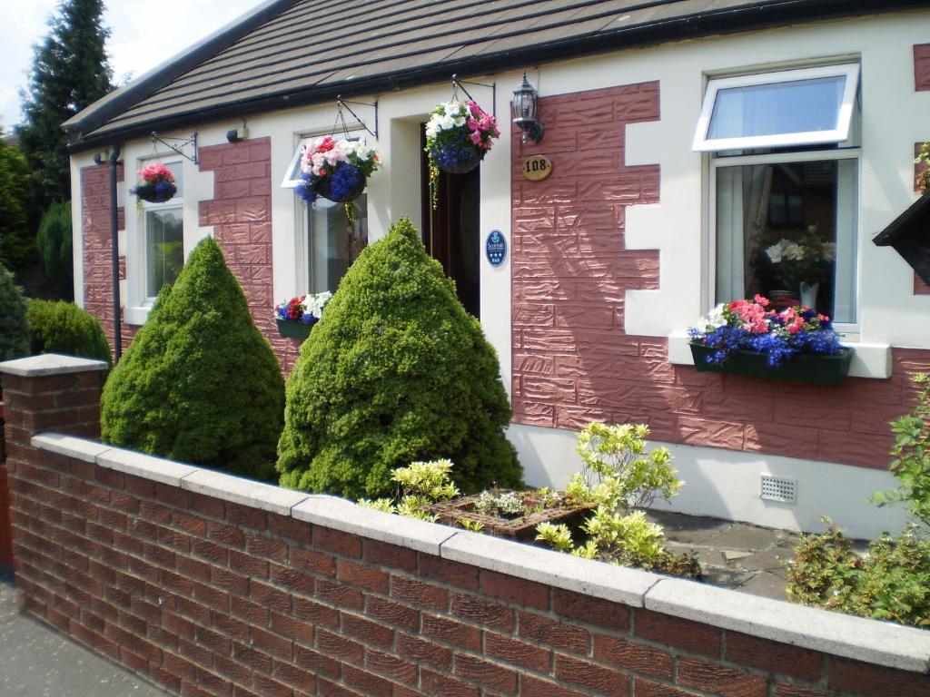 a red brick house with trees in front of it at Shawlee Cottage in Airdrie