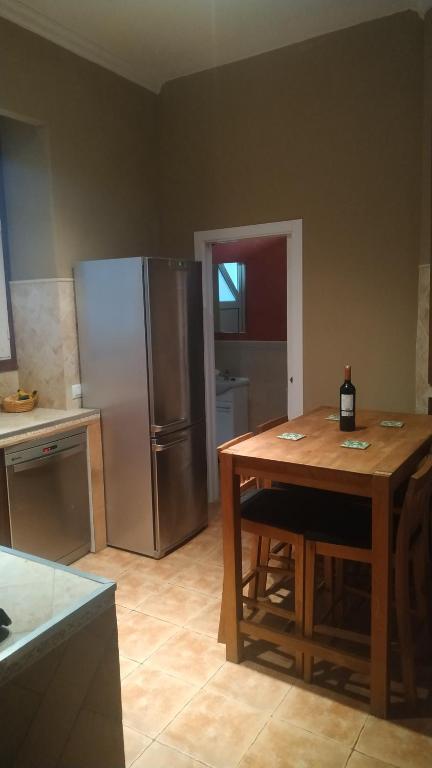 a kitchen with a wooden table and a refrigerator at Apartamento Cruz Vieja in Jerez de la Frontera