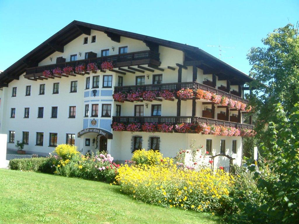 ein großes weißes Gebäude mit Blumen davor in der Unterkunft Gasthof zur Alten Post in Regen