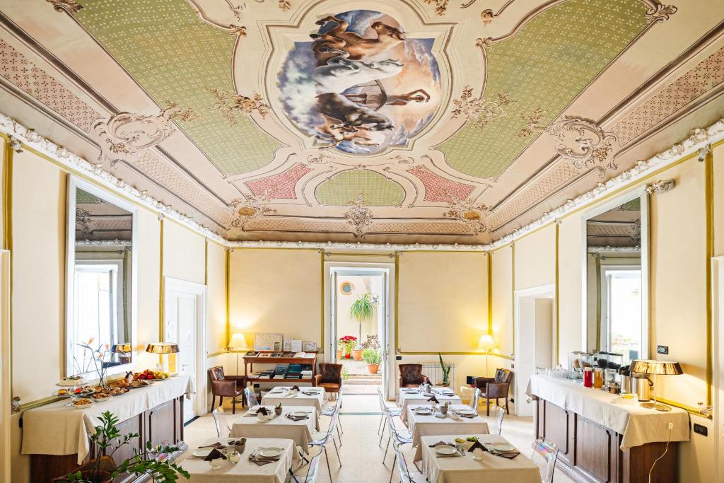 B&B Sant'Agostino في باليرمو: غرفة طعام بها طاولات وكراسي وسقف