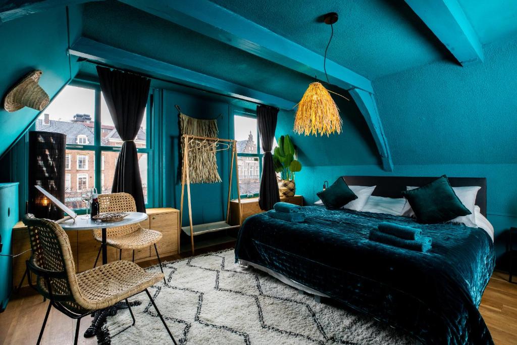 una camera blu con un letto e un tavolo con sedie di Bambu Sleep Boutique a Haarlem