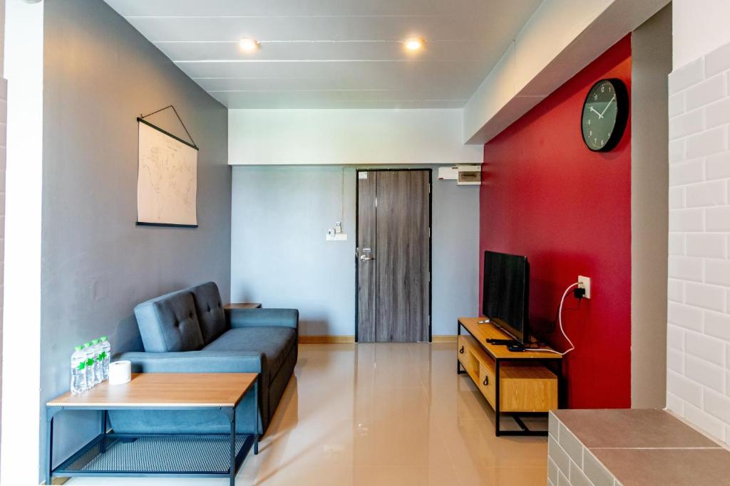 Living Naraa Place في بانكوك: غرفة معيشة مع أريكة زرقاء وجدار احمر
