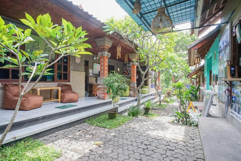 a building with a porch with trees in front of it at Padi-Padi Hostel & Bar in Ubud