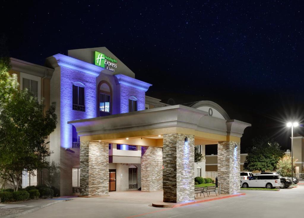 un hotel con un edificio iluminado en azul por la noche en Holiday Inn Express & Suites Dallas - Duncanville, an IHG Hotel, en Duncanville