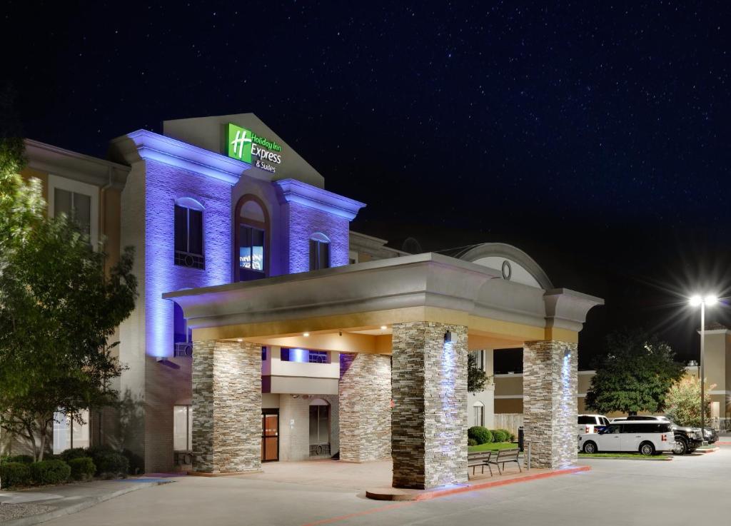 un hôtel avec un bâtiment éclairé en bleu la nuit dans l'établissement Holiday Inn Express & Suites Dallas - Duncanville, an IHG Hotel, à Duncanville