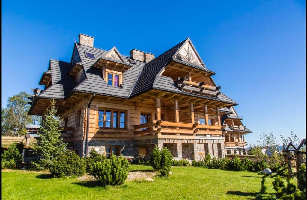 uma grande casa de madeira com um telhado de gambrel em udanypobyt House Million Dollar View em Gliczarów Górny