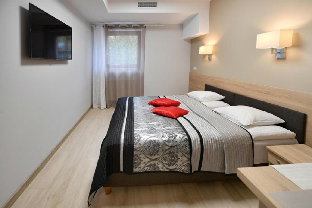Un dormitorio con una cama con almohadas rojas. en Fotex, en Ząbki