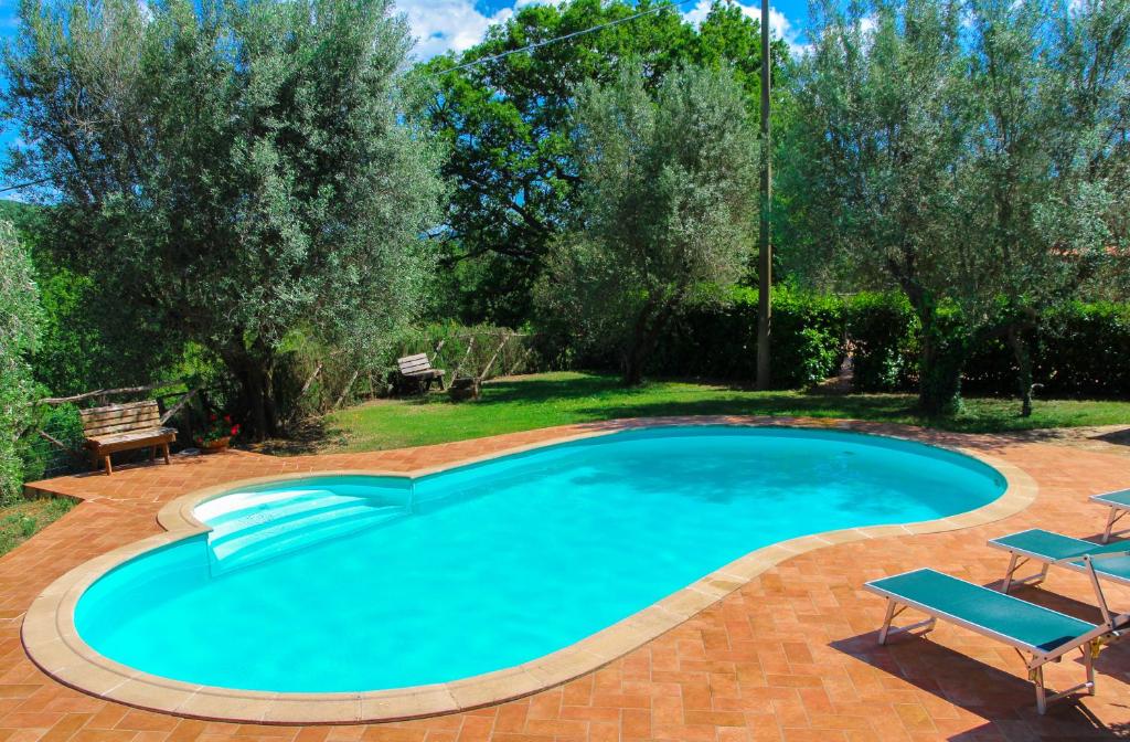 a swimming pool in a yard with two chairs and trees at Agriturismomillefiori in Manciano