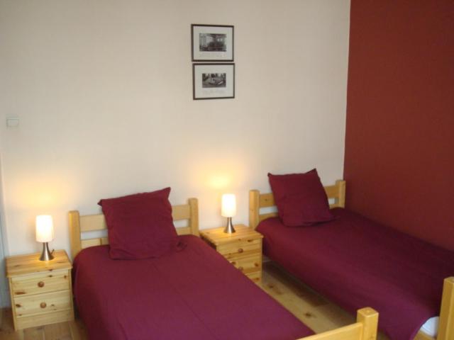 2 Betten in einem Zimmer mit lila Laken und Lampen in der Unterkunft LE CHAT NOIR in Ypern