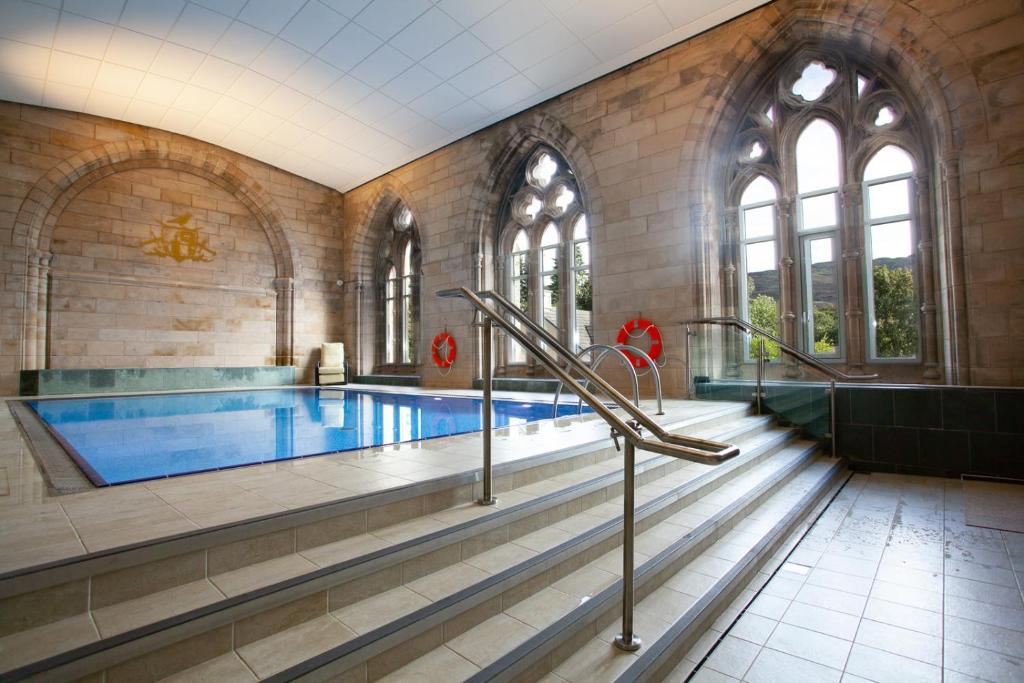 a large swimming pool in a large building with a swimming pool at Loch Ness Abbey Cottages in Fort Augustus