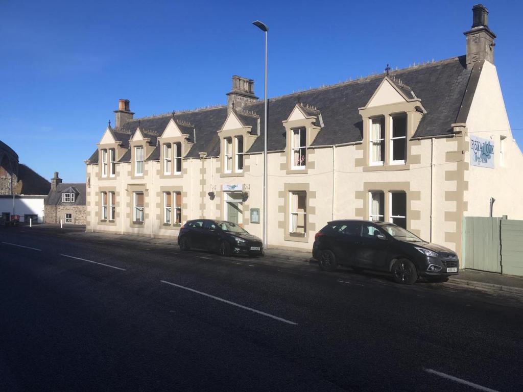 dois carros estacionados em frente a um grande edifício em The Royal Oak Hotel em Cullen