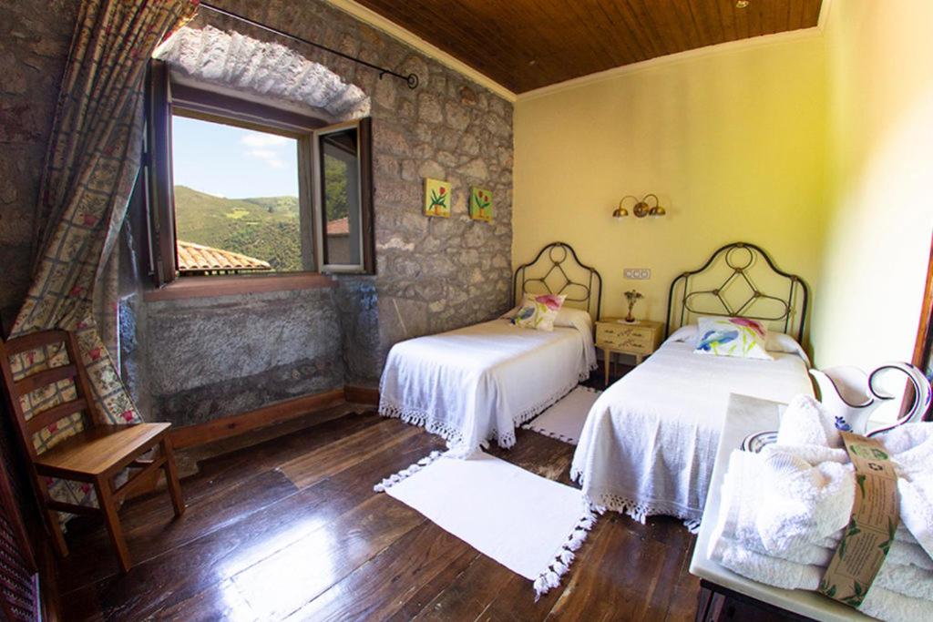 a bedroom with two beds and a window at Agroturismo La Casona de Belmonte in Oviñana
