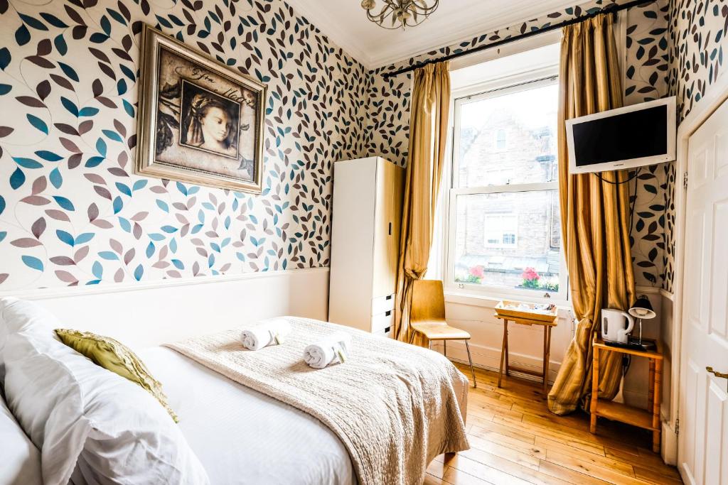 een slaapkamer met een bed en een muur bedekt met behang bij Balmore Guest House in Edinburgh