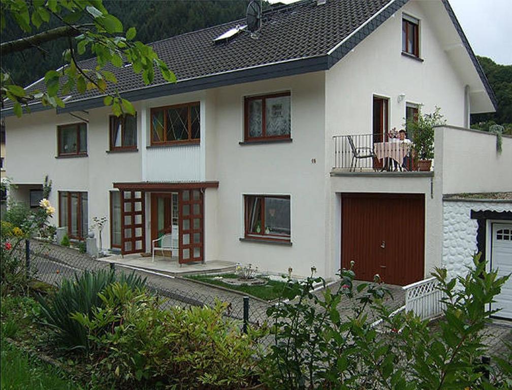 a white house with a person sitting on a balcony at Regina's Gästehaus in Weisenbach