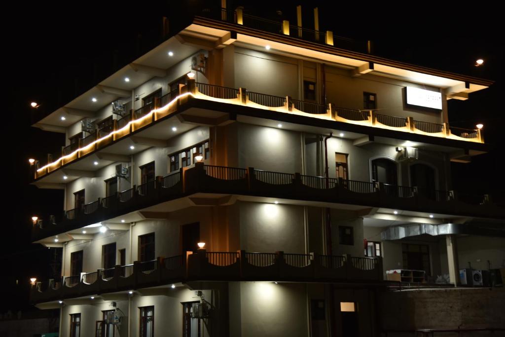 a building with lights on the side of it at night at Mastiff Wildcrest Outer Dharamshala Near Chamunda Devi Temple in Pālampur