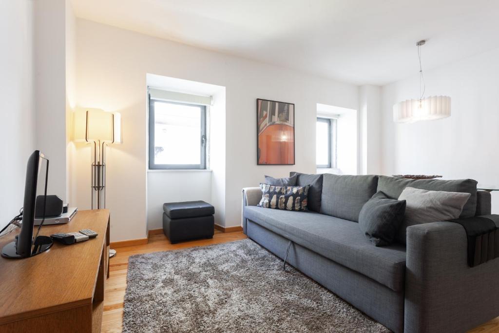 a living room with a gray couch and a tv at FLH Liberdade Contemporary Flat in Lisbon