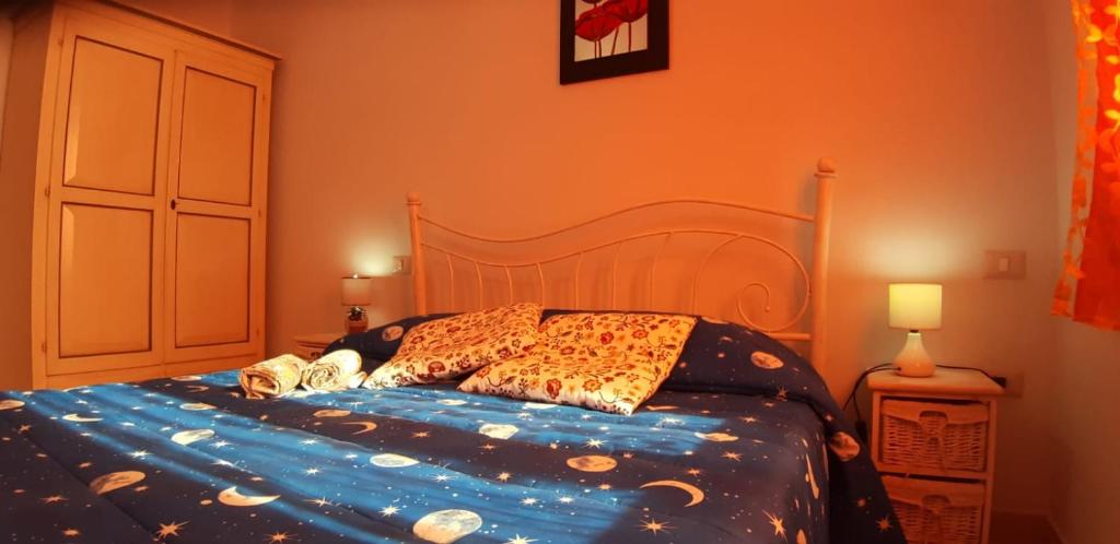 łóżko z niebieską kołdrą i poduszkami w obiekcie Il Girasole w mieście SantʼAntìoco