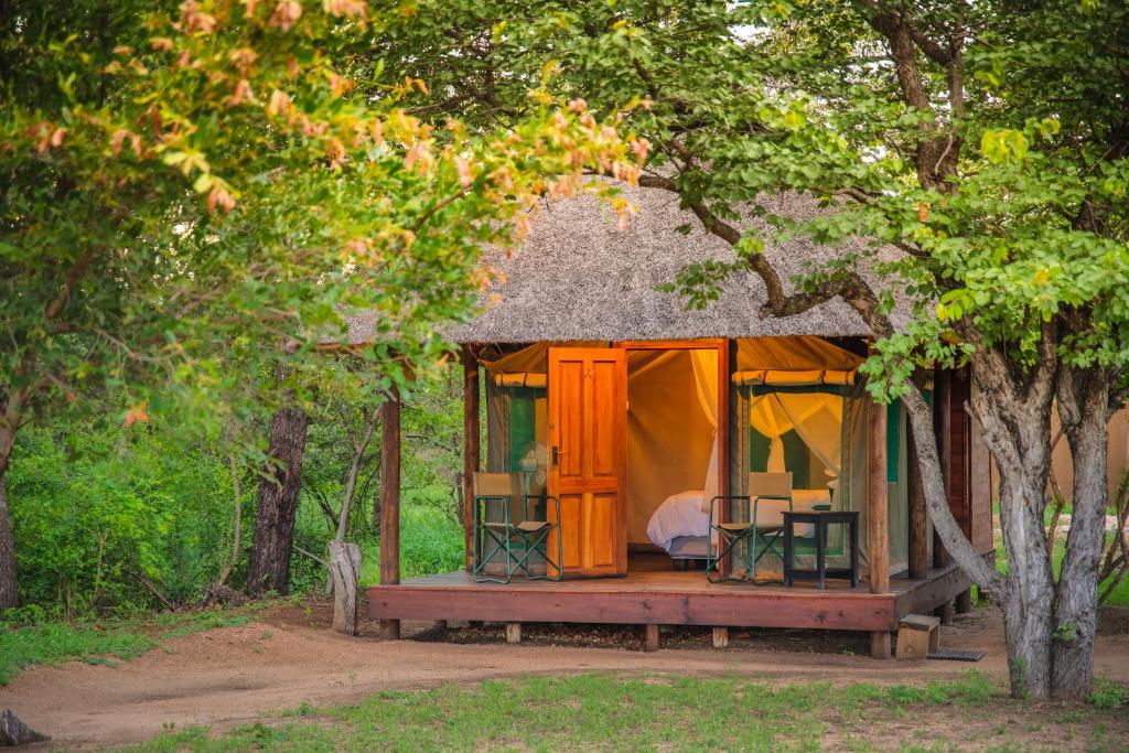 a cabin in the woods with a table and chairs at Shindzela Tented Camp in Timbavati Game Reserve