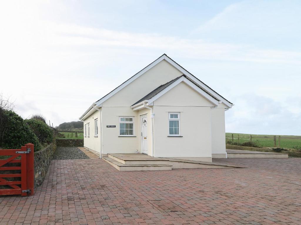 un pequeño edificio blanco en una entrada de ladrillo en Bryn Eiddon, en Pwllheli