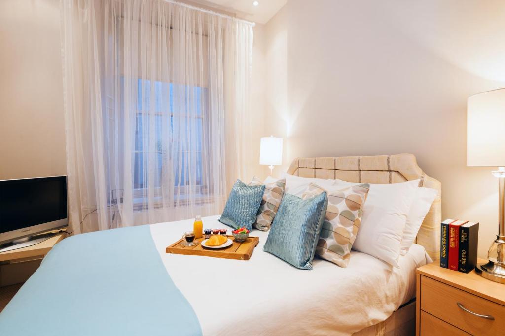 a bedroom with a bed with a tray of food on it at All2Stay South Kensington Apartment in London