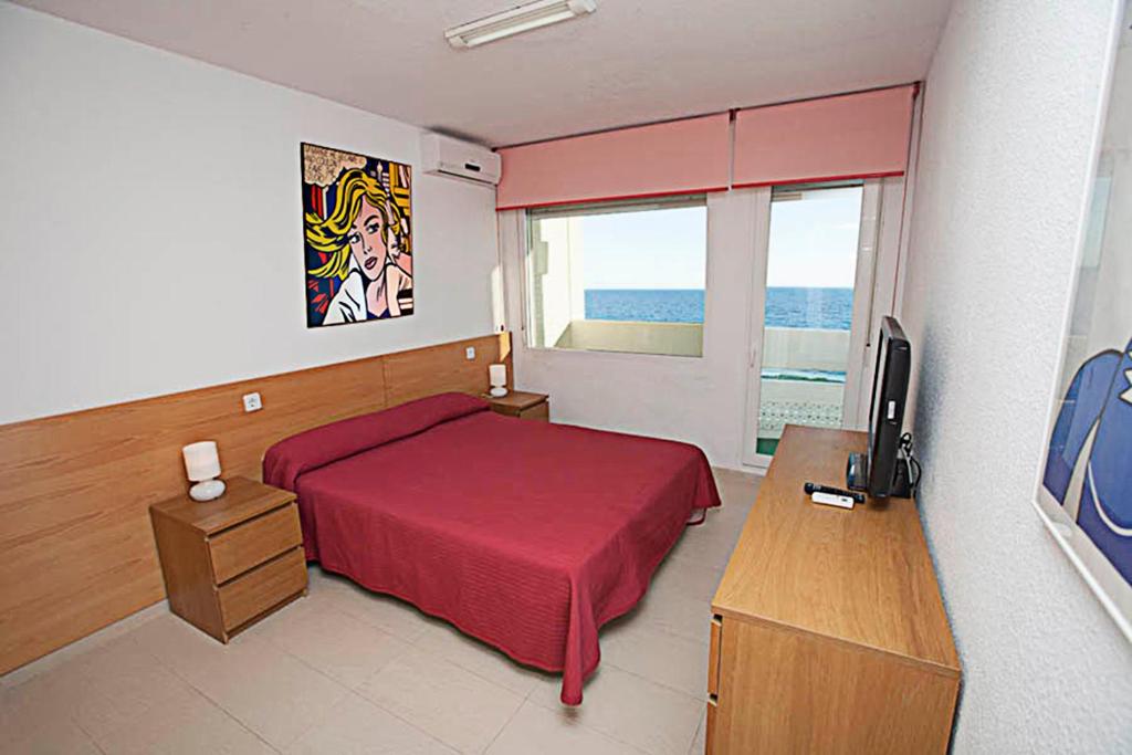 Dormitorio con cama, escritorio y TV en Apartamento con vistas al mar primera linea playa Matalascañas, en Matalascañas