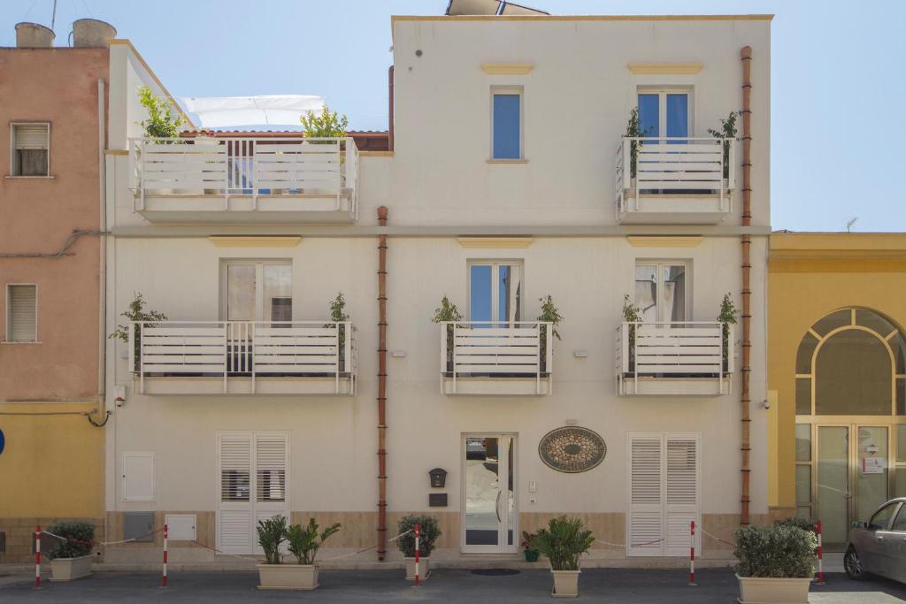 マルサラにあるIl Sogno Apartmentsの白いバルコニーと鉢植えの植物がある建物