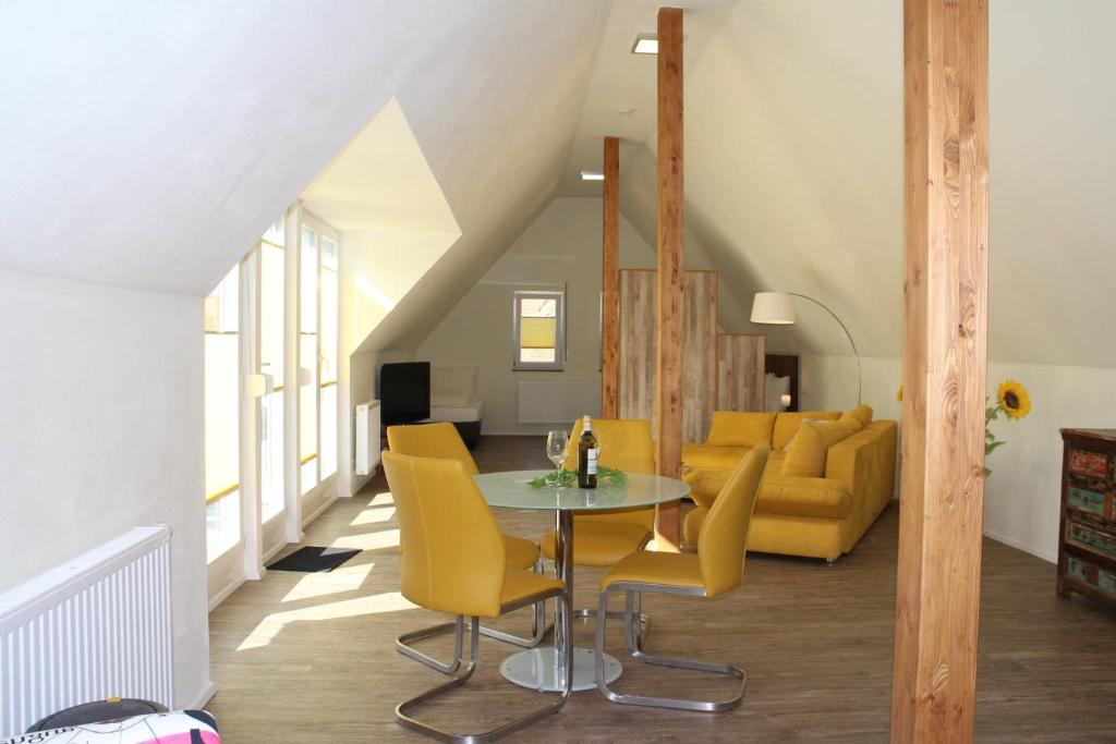 a living room with a table and yellow chairs at Gräfin von Paris - Appartement mit Saunanutzung in Burgbernheim