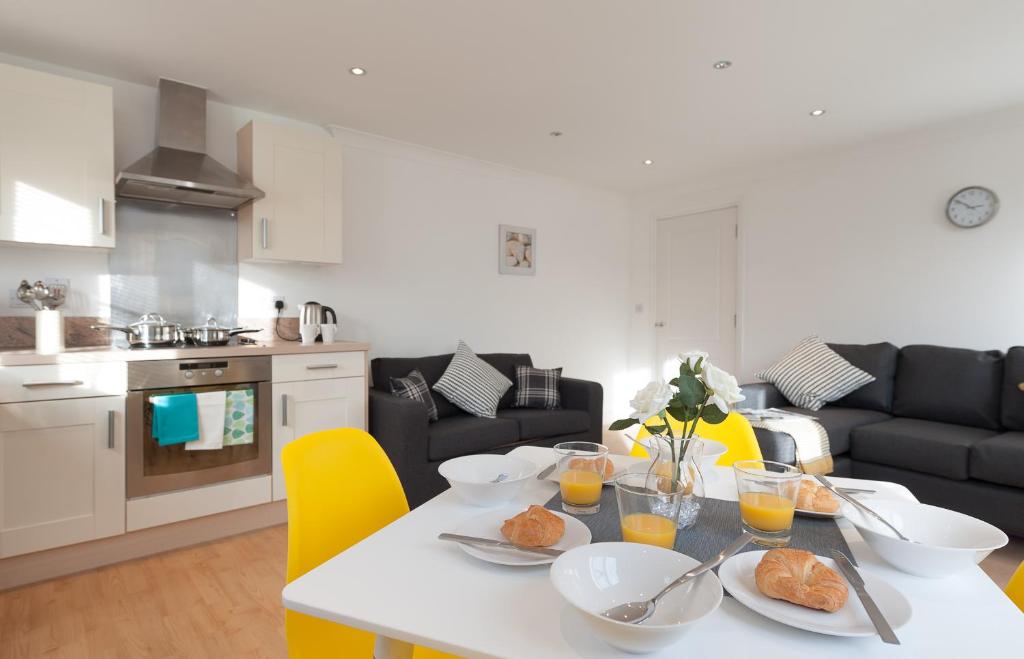 a kitchen and living room with a table with food on it at Treeview Apartment- A lovely 2 bed apartment near Colchester North Station by Catchpole Stays in Colchester
