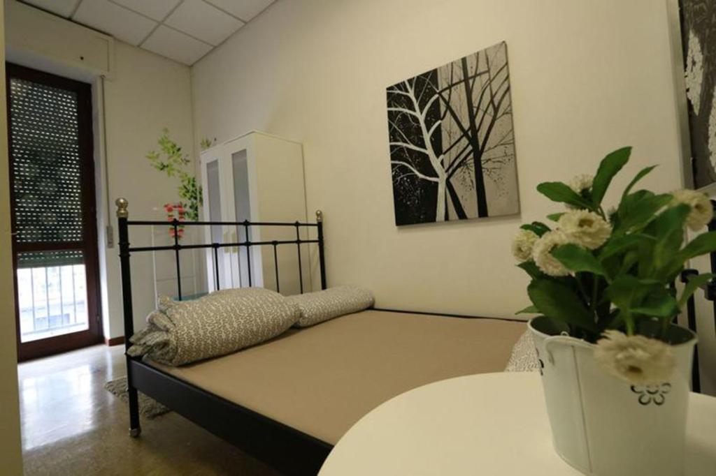 Habitación con cama y jarrón con flores en Panda Hostel en Milán