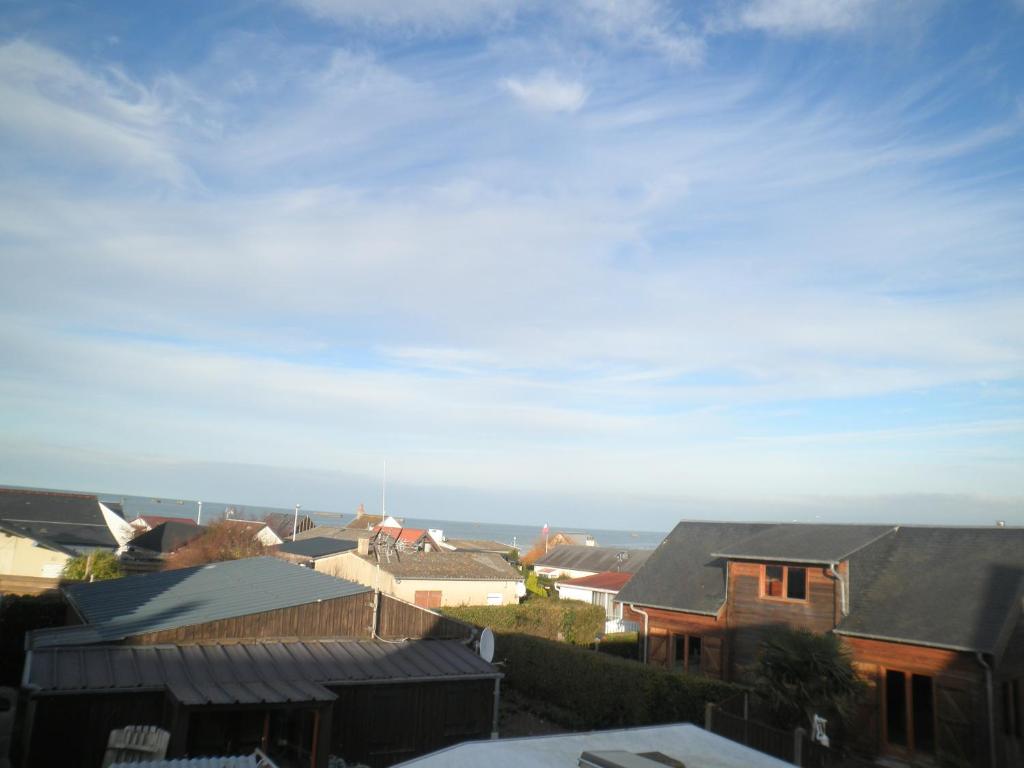 - une vue sur une ville avec des maisons et l'océan dans l'établissement Appartement F1 mansardé à 100m de la plage, proche de Arromanches et des plages du Débarquement, à Saint-Côme-de-Fresné