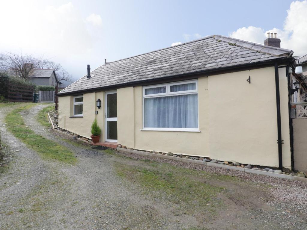 a small house on a gravel road at The Old Coach House in Penmaen-mawr