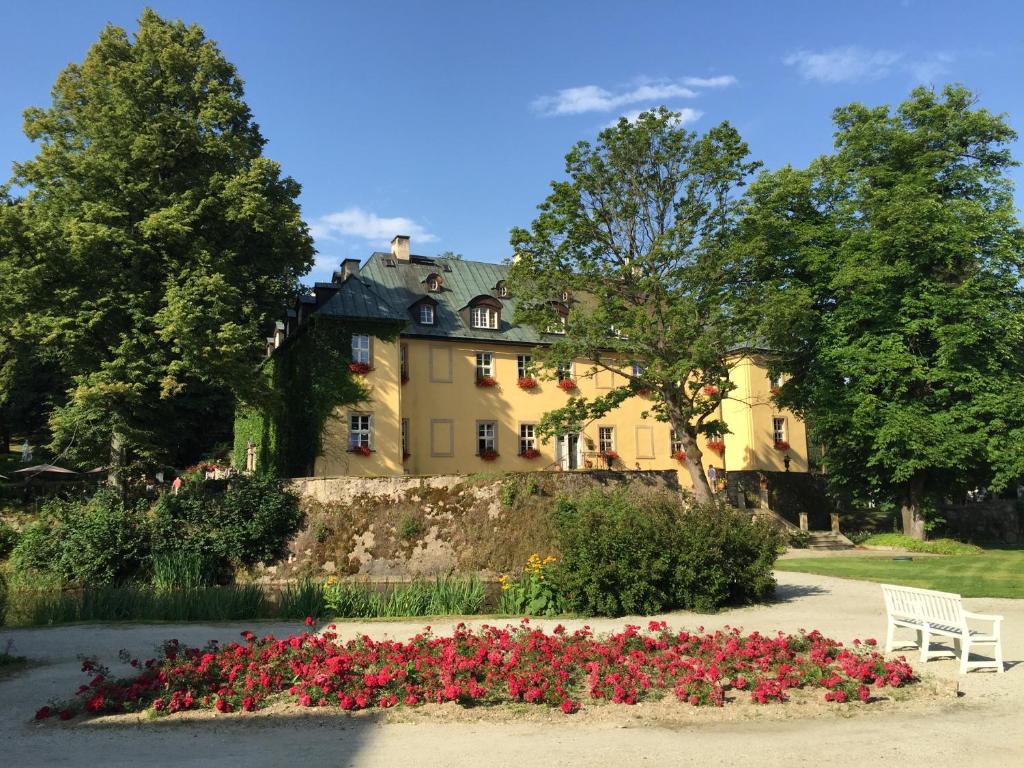 イェレニャ・グラにあるHotel Palac Staniszowの花の前に白いベンチを持つ家