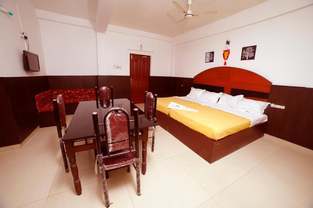 a bedroom with a bed and a table and chairs at Kairali Tourist Home in Guruvāyūr