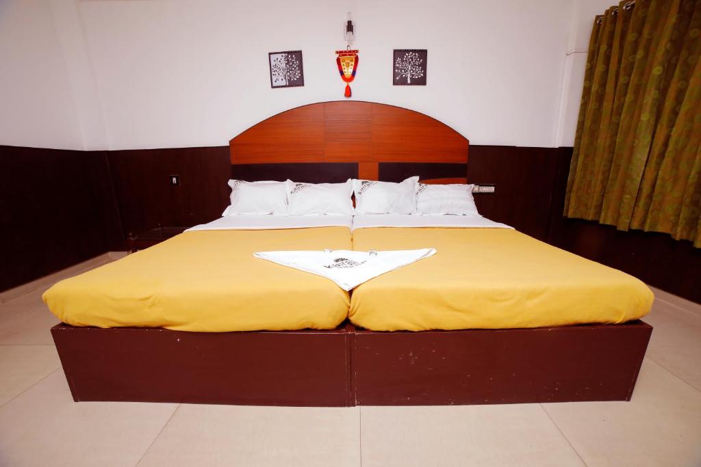 a bedroom with a large bed with a yellow blanket at Kairali Tourist Home in Guruvāyūr