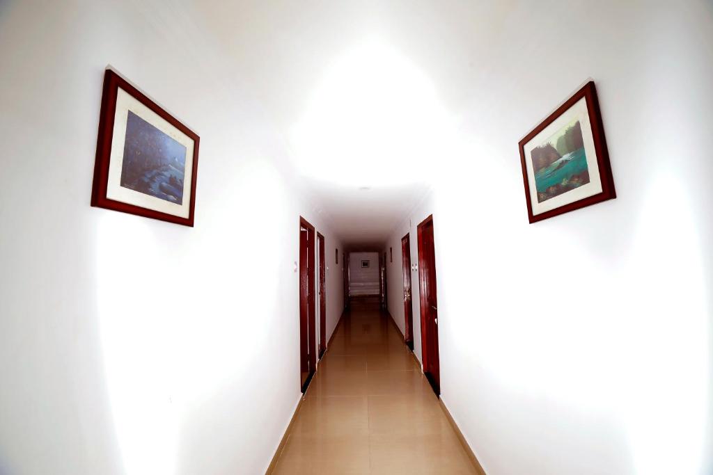 a corridor with two pictures on the walls and a hallway with two doors at Kairali Tourist Home in Guruvāyūr