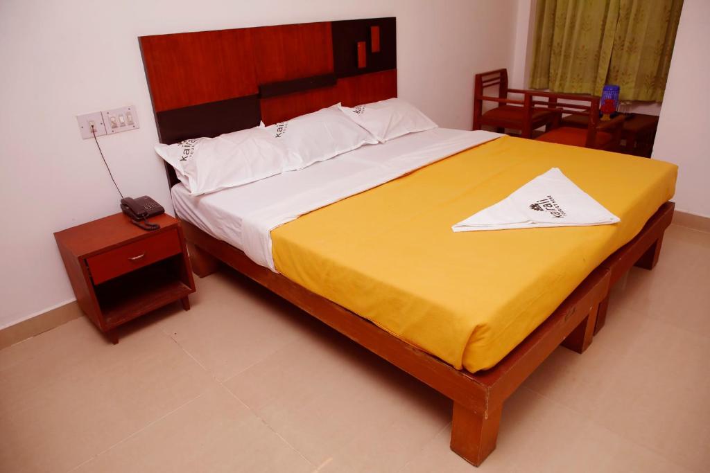 a bedroom with a large bed with a yellow blanket at Kairali Tourist Home in Guruvāyūr