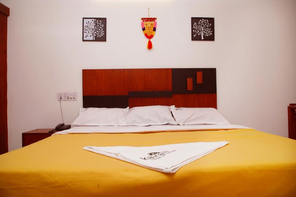a yellow bed with two white towels on it at Kairali Tourist Home in Guruvāyūr