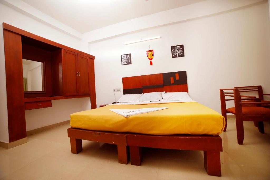 a bedroom with a bed and a table and a chair at Kairali Tourist Home in Guruvāyūr